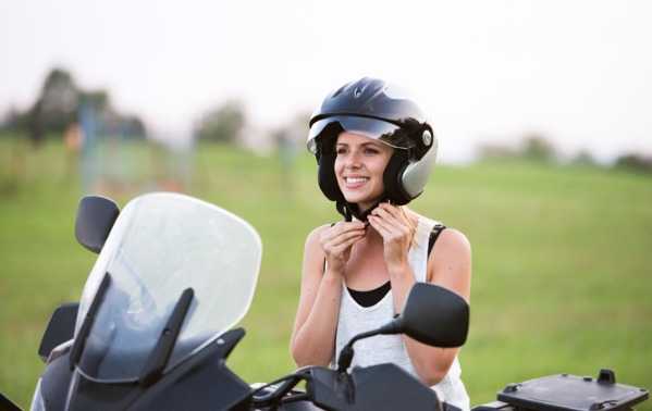 Mujer poniéndose el casco en una moto 