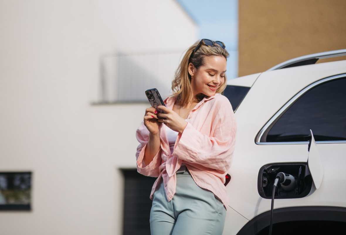 Mujer junto a su coche eléctrico